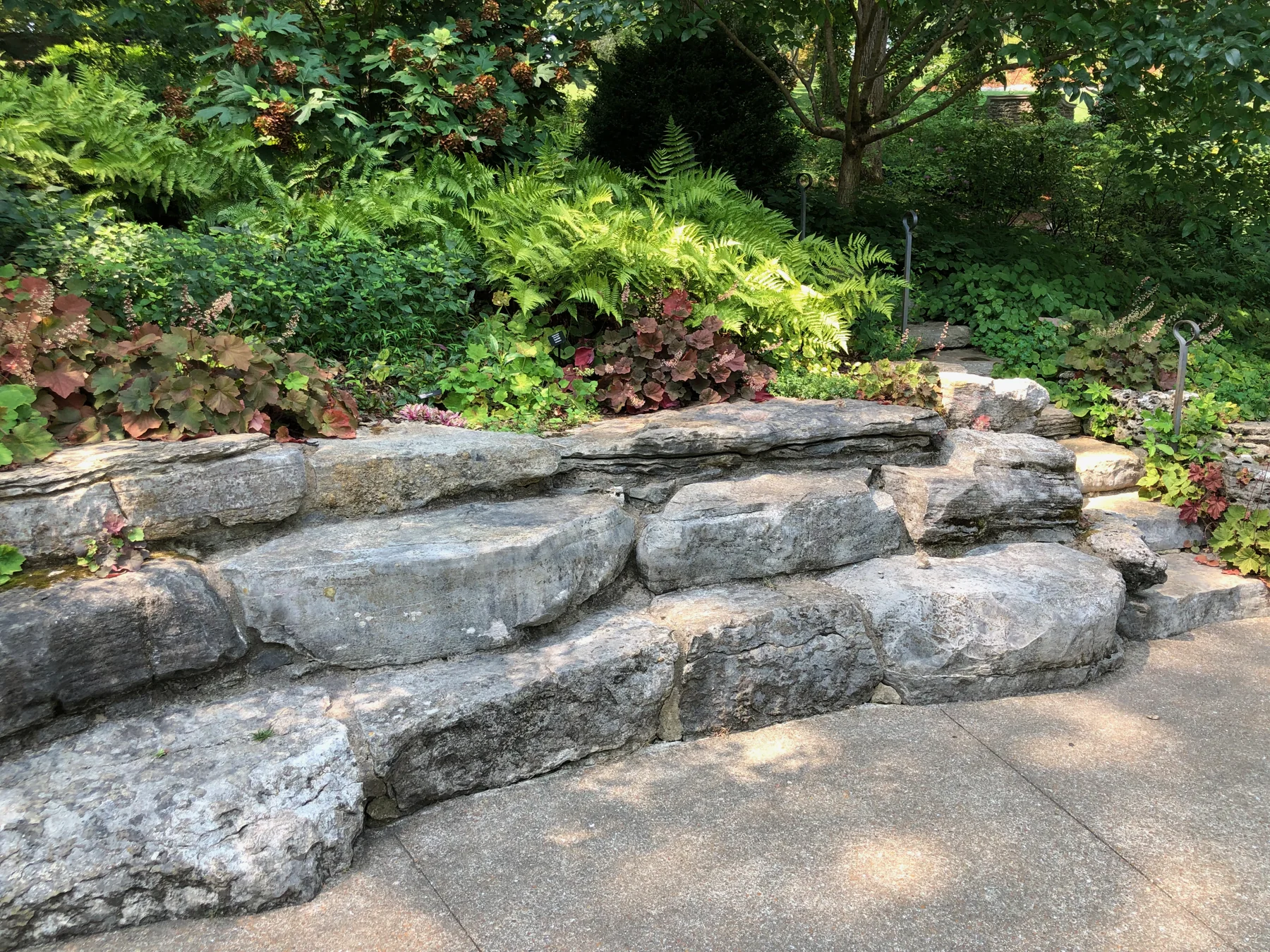 Layered natural stone retaining wall with planted beds and a curved walkway